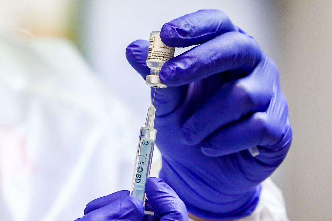 Un sanitario manejando una vacuna de Pfizer Un sanitario manejando una vacuna de Pfizer