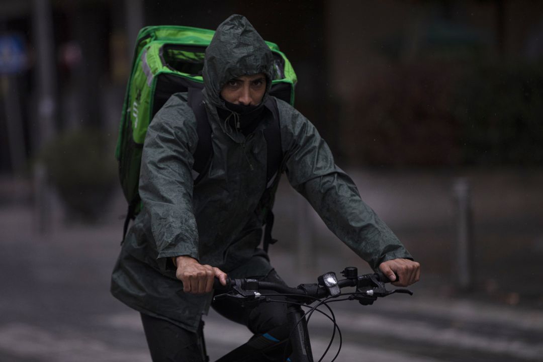 Un rider (repartidor) trabaja bajo la lluvia protegido con un impermeable. En Sevilla. Un rider (repartidor) trabaja bajo la lluvia protegido con un impermeable. En Sevilla.