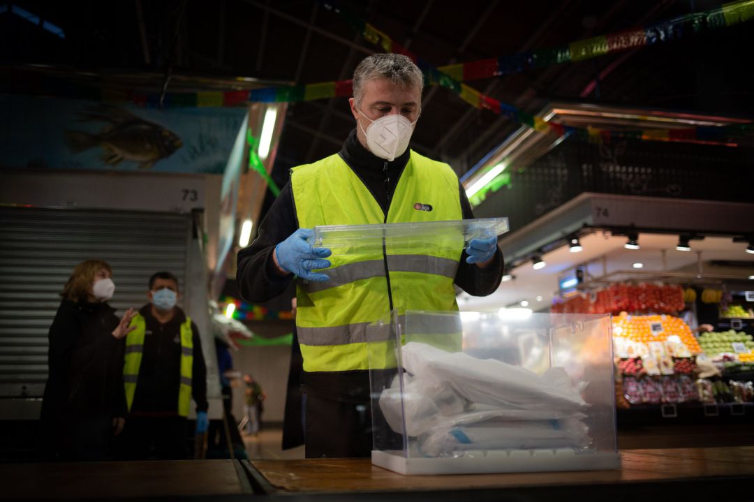 Un operario coloca las urnas y papeletas electorales en una mesa Un operario coloca las urnas y papeletas electorales en una mesa