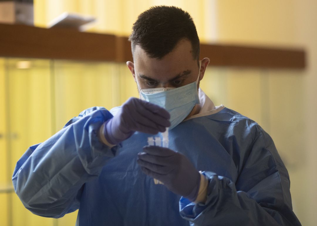 Un trabajador sanitario sostiene una probeta en un dispositivo de cribado masivo de antígenos. Un trabajador sanitario sostiene una probeta en un dispositivo de cribado masivo de antígenos.
