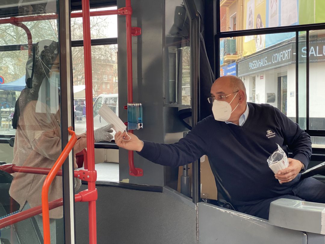 El conductor de l'autobús urbà repartint mascaretes El conductor de l'autobús urbà repartint mascaretes