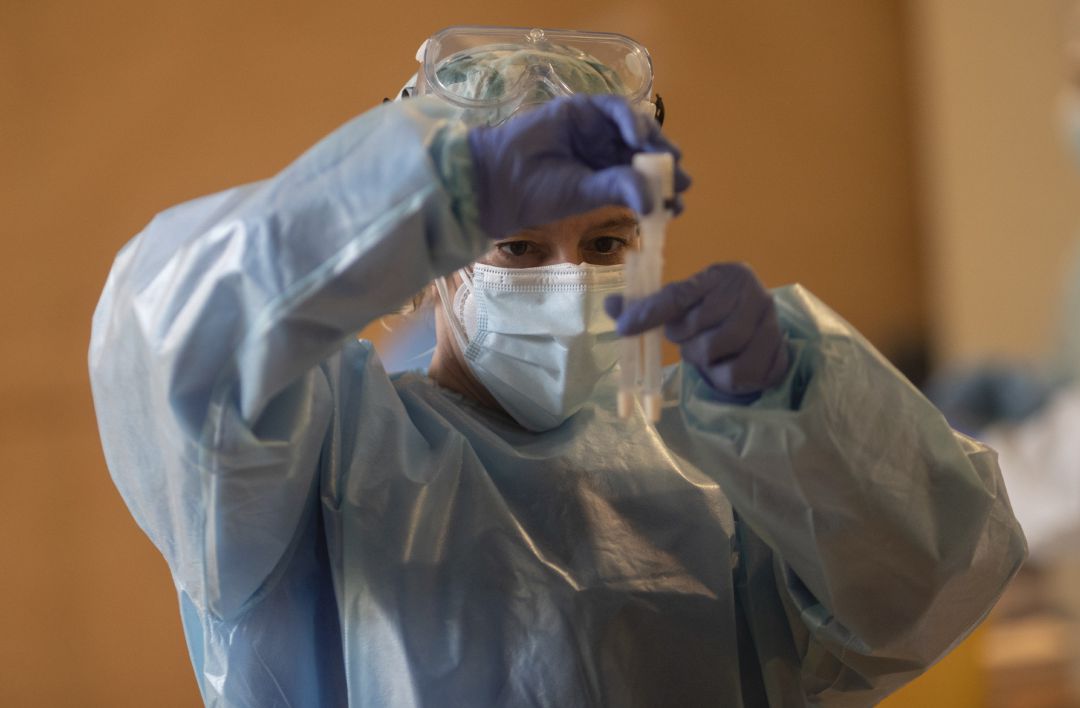 Un trabajador sanitario sostiene una probeta en un dispositivo de cribado masivo de antígenos. Un trabajador sanitario sostiene una probeta en un dispositivo de cribado masivo de antígenos.