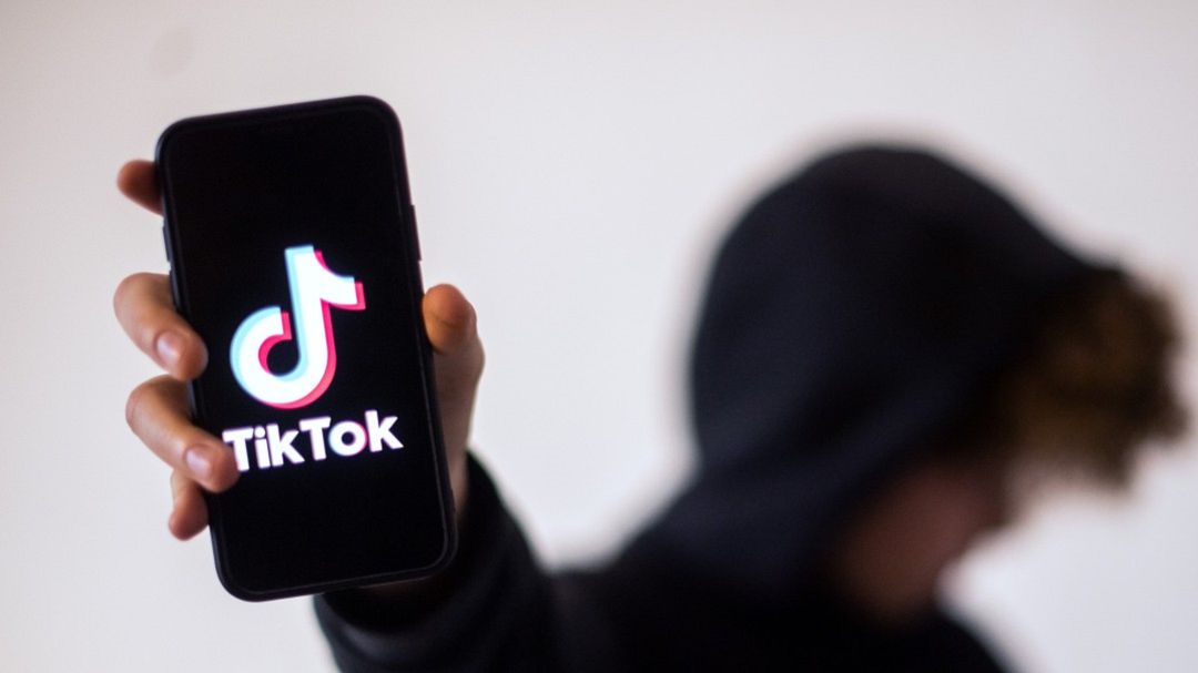 Un jóven sujetando su móvil en el que se ve el logotipo de Tik Tok. Un jóven sujetando su móvil en el que se ve el logotipo de Tik Tok.