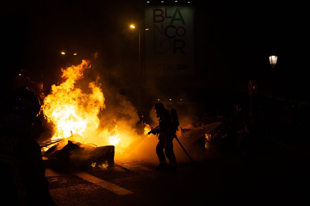 Bomberos apagan un incendio provocado por los manifestantes que apoyan a Pablo Hasel durante los disturbios en Barcelona Bomberos apagan un incendio provocado por los manifestantes que apoyan a Pablo Hasel durante los disturbios en Barcelona