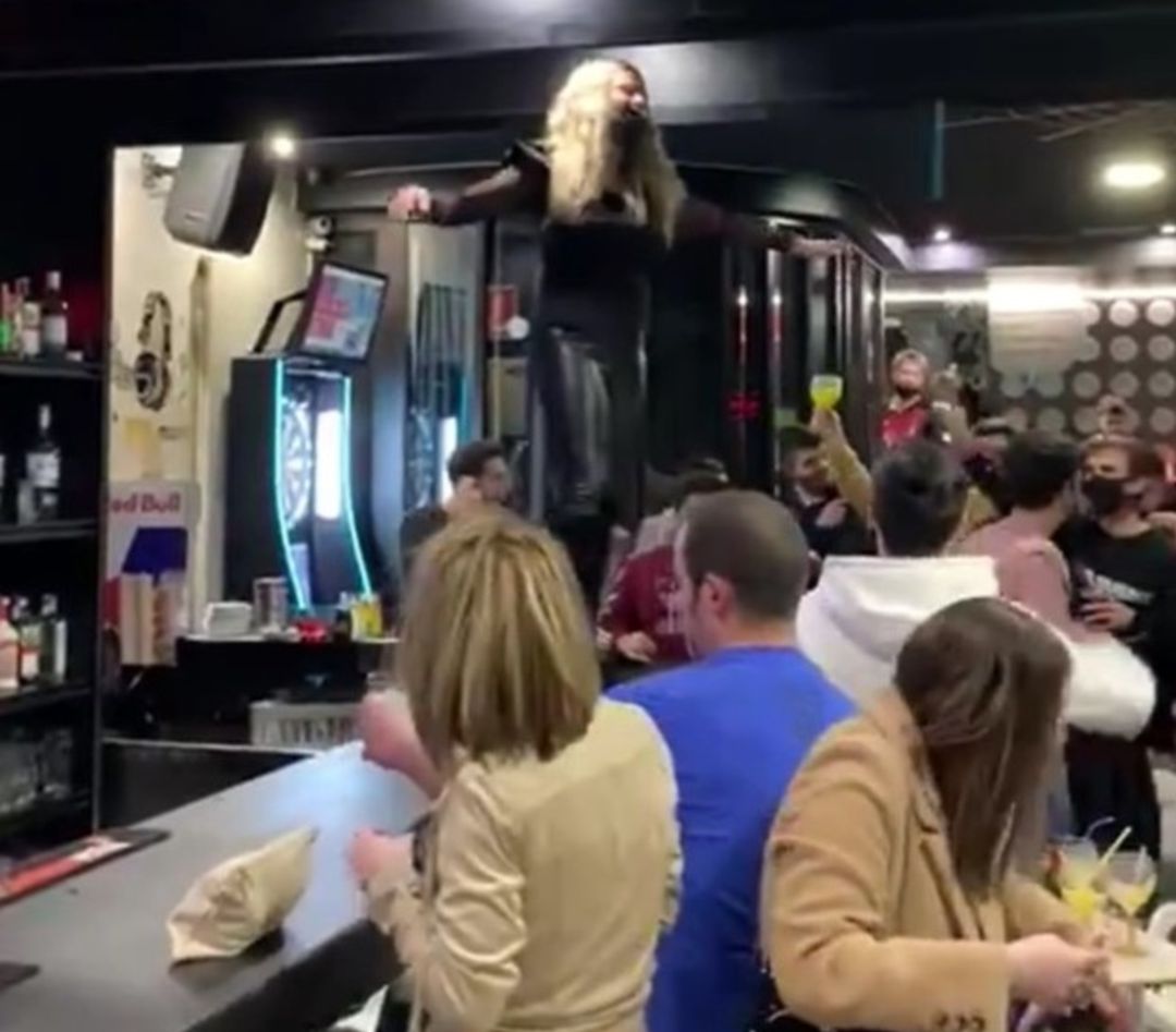 Una mujer baila encima de la barra mientras los demás jalean. Una mujer baila encima de la barra mientras los demás jalean.