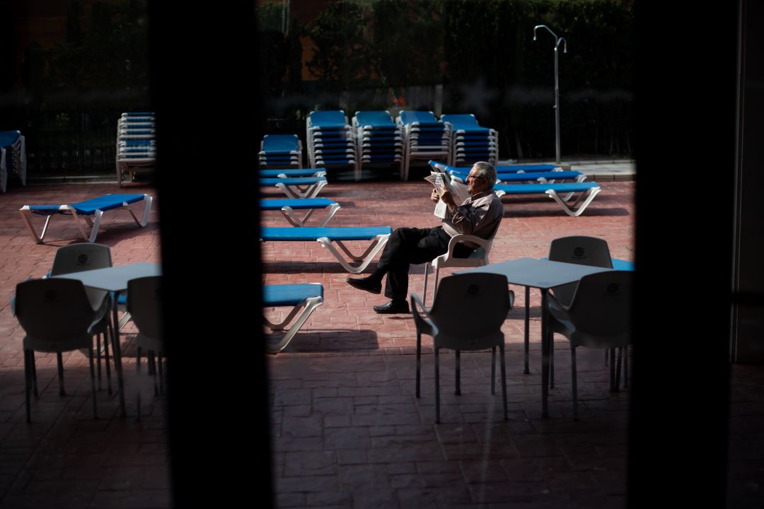 Un hombre lee el periódico en el recinto de la piscina de un hotel Un hombre lee el periódico en el recinto de la piscina de un hotel