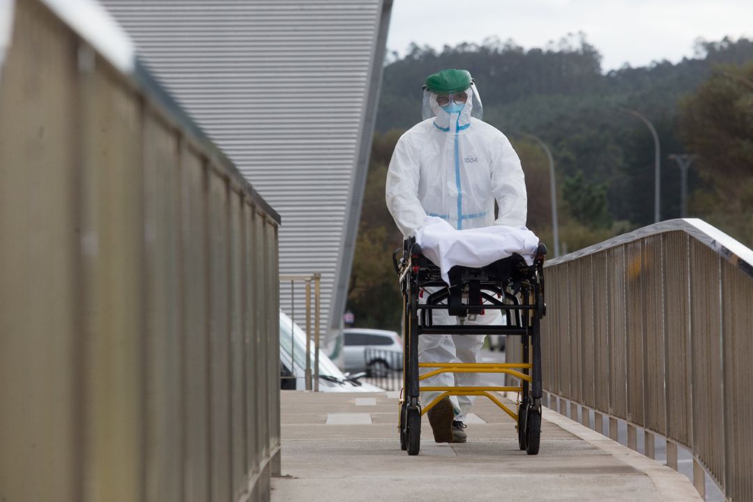 Un trabajador sanitario totalmente protegido traslada una camilla en las inmediaciones de la residencia de ancianos de San Cibrao (Lugo) Un trabajador sanitario totalmente protegido traslada una camilla en las inmediaciones de la residencia de ancianos de San Cibrao (Lugo)