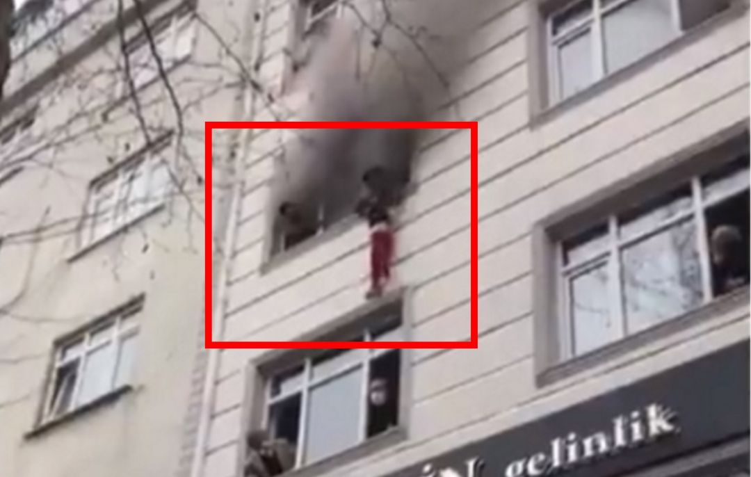 Captura del momento en el que la madre lanza a uno de sus hijos por la ventana. Captura del momento en el que la madre lanza a uno de sus hijos por la ventana.
