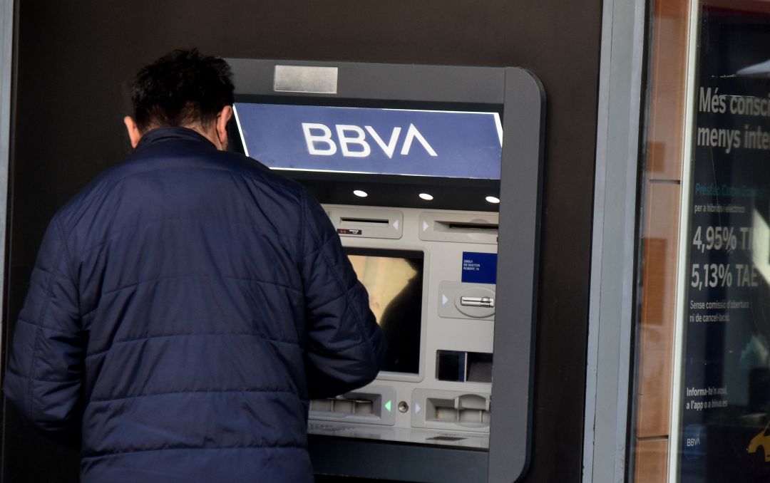 Un hombre saca dinero frente a un cajero. Un hombre saca dinero frente a un cajero.