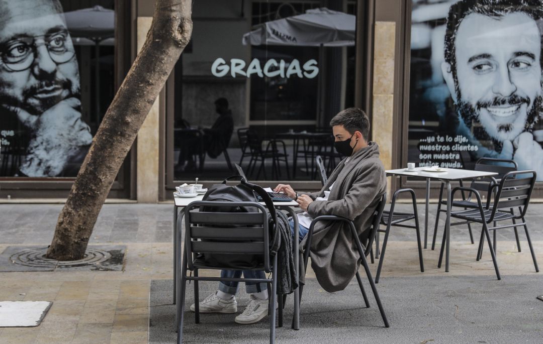 Un joven trabaja con su ordenador portátil en una terraza en España Un joven trabaja con su ordenador portátil en una terraza en España