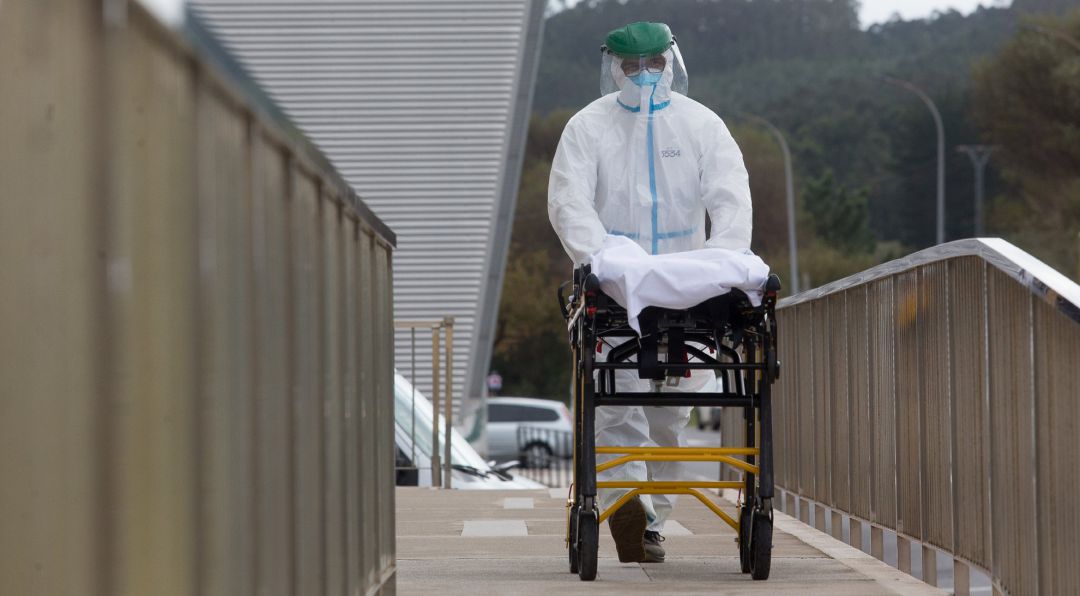 Un trabajador sanitario totalmente protegido traslada una camilla en las inmediaciones de la residencia de ancianos de San Cibrao, Lugo, en 9 de noviembre de 2020. Un trabajador sanitario totalmente protegido traslada una camilla en las inmediaciones de la residencia de ancianos de San Cibrao, Lugo, en 9 de noviembre de 2020.