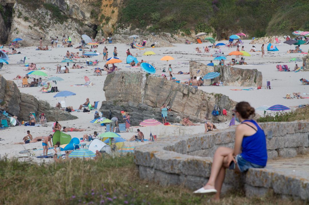 Una persona sentada frente a la playa en A Mariña en julio de 2020. Una persona sentada frente a la playa en A Mariña en julio de 2020.