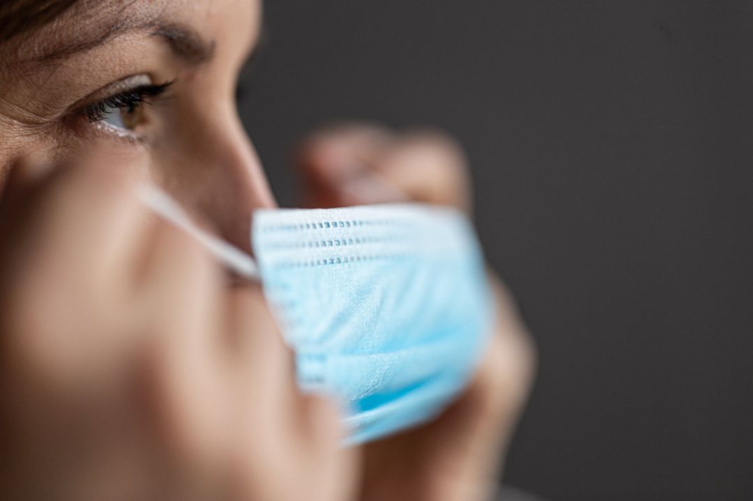 Una mujer se coloca una mascarilla tras haberle puesto otra a su hijo Una mujer se coloca una mascarilla tras haberle puesto otra a su hijo