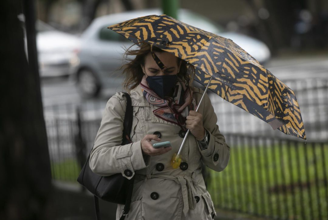 Una mujer camina bajo su paraguas durante un día lluvioso y con rachas de viento. Una mujer camina bajo su paraguas durante un día lluvioso y con rachas de viento.