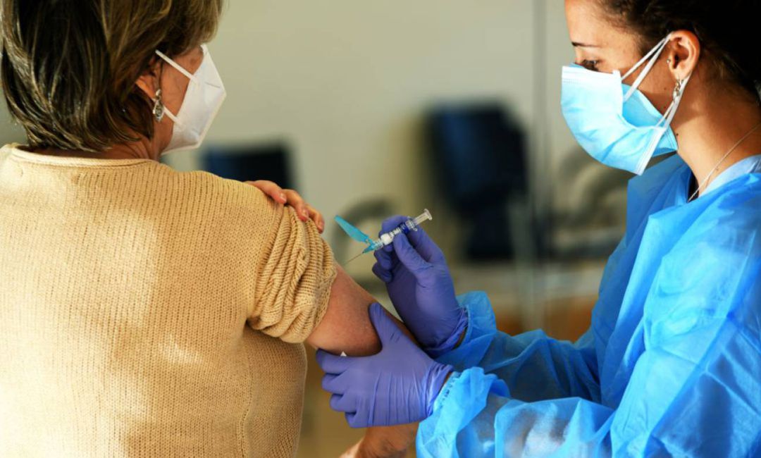 Personal sanitario administra la vacuna a una mujer. Personal sanitario administra la vacuna a una mujer.