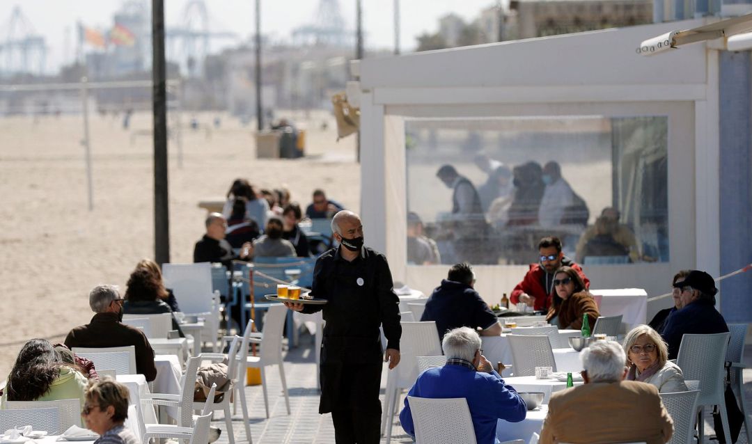 Un camarero atiende las mesas de una terraza en uno de los restaurantes de la playa de la playa de la Malvarrosa de Valéncia Un camarero atiende las mesas de una terraza en uno de los restaurantes de la playa de la playa de la Malvarrosa de Valéncia