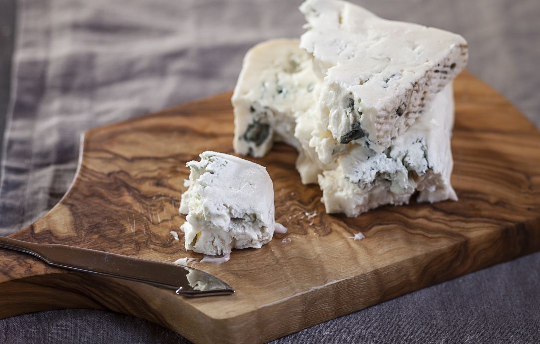 Pieza de queso gorgonzola en una tabla de cortar. Pieza de queso gorgonzola en una tabla de cortar.