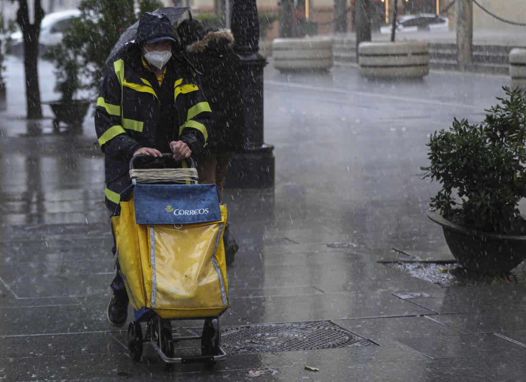 Un repartidor de Correos trabaja bajo la lluvia en una foto de archivo Un repartidor de Correos trabaja bajo la lluvia en una foto de archivo