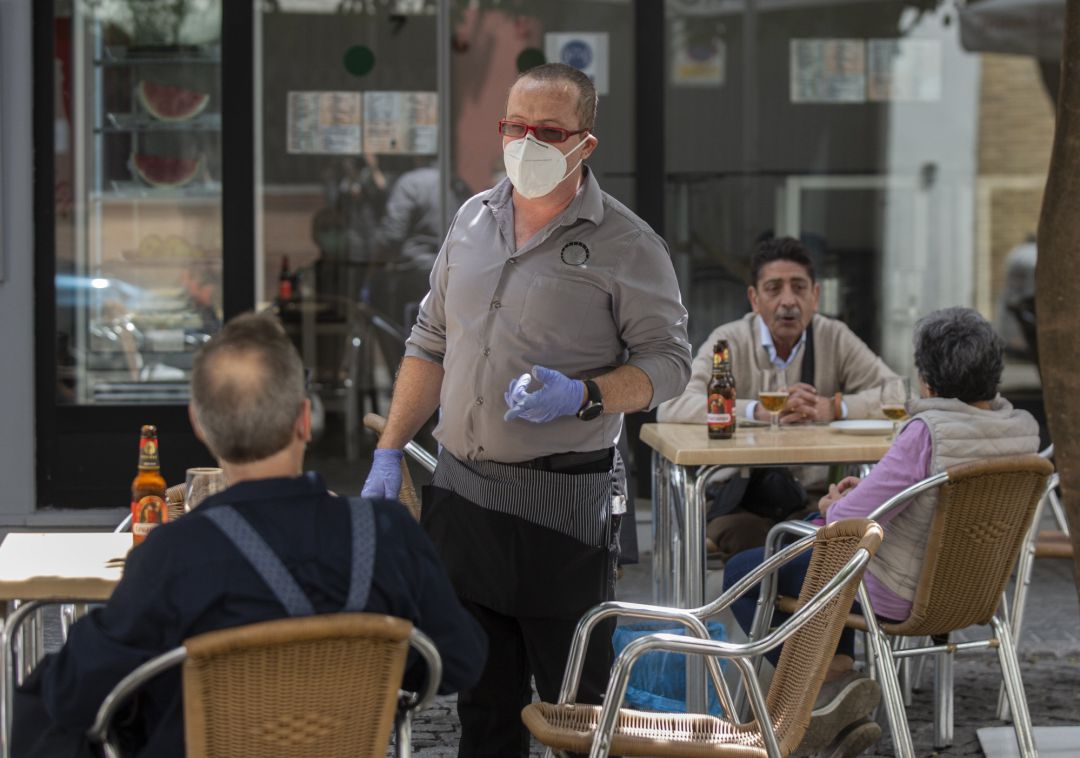 Un camarero atiende la terraza de un bar en Sevilla Un camarero atiende la terraza de un bar en Sevilla