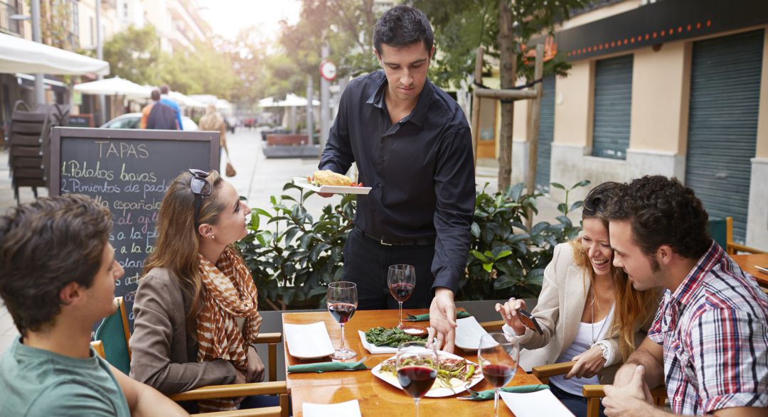 Un camamero sirve una comanda en un restaurante Un camamero sirve una comanda en un restaurante