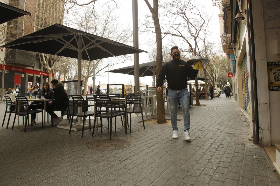 Un camarero atiende a varios clientes en la terraza de un bar Un camarero atiende a varios clientes en la terraza de un bar