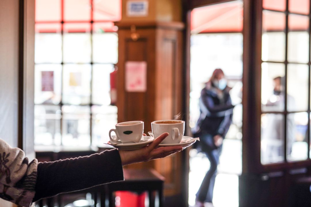 Un camarero sirve varios cafés en una cafetería Un camarero sirve varios cafés en una cafetería