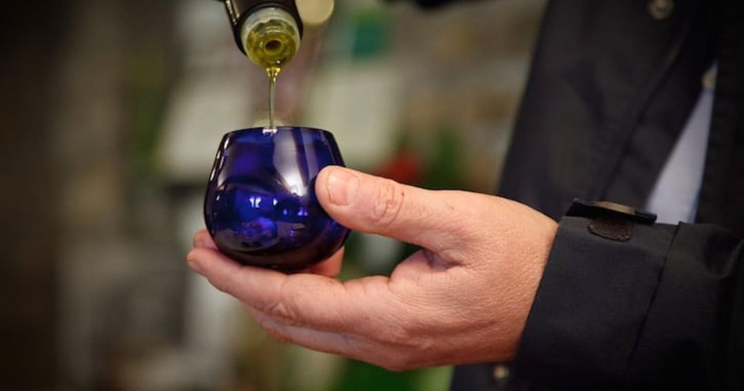 Un hombre echa aceite de oliva en un vaso de cata. Un hombre echa aceite de oliva en un vaso de cata.