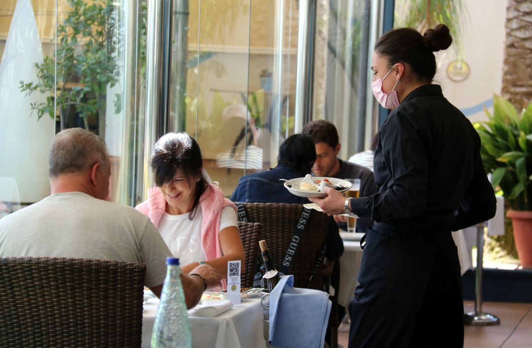 Pla mitjà d'una cambrera servint plats a dos clients al restaurant de l'Hotel Miami de Sant Carles de la Ràpita. Pla mitjà d'una cambrera servint plats a dos clients al restaurant de l'Hotel Miami de Sant Carles de la Ràpita.