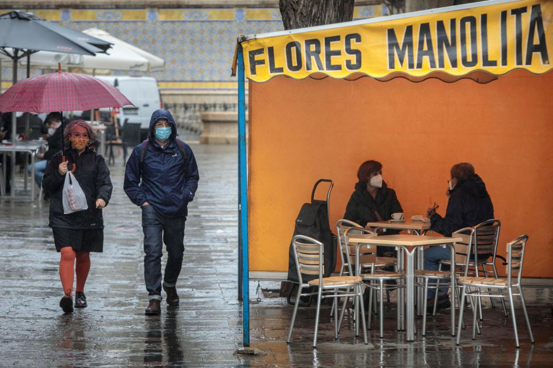Dos personas en la terraza de un bar protegidas de la lluvia por un toldo de un puesto de flores. Dos personas en la terraza de un bar protegidas de la lluvia por un toldo de un puesto de flores.