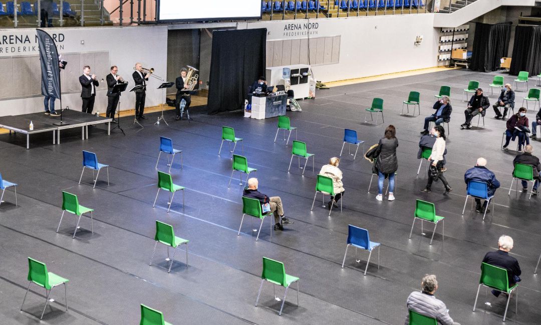Ciudadanos daneses esperan a ser vacunados, con separación y ambientación musical. Ciudadanos daneses esperan a ser vacunados, con separación y ambientación musical.