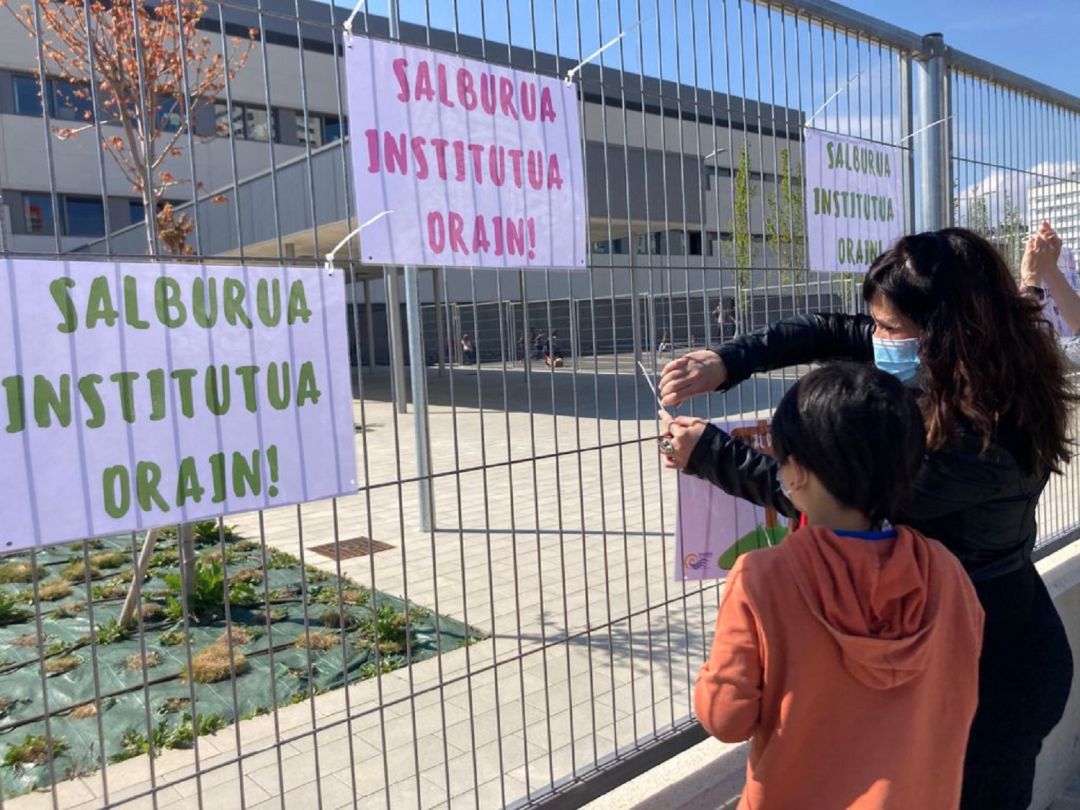 Un alumno de Ekabarri y una madre de los alumnos del colegio cuelgan carteles bajo el lema "instituto de Salburua ya" en las verjas de la puerta principal del colegio. Un alumno de Ekabarri y una madre de los alumnos del colegio cuelgan carteles bajo el lema "instituto de Salburua ya" en las verjas de la puerta principal del colegio.
