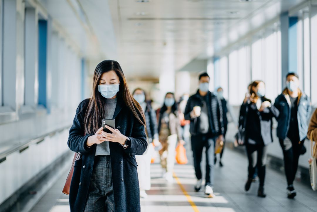 Una mujer utiliza su teléfono móvil con la mascarilla puesta. Una mujer utiliza su teléfono móvil con la mascarilla puesta.