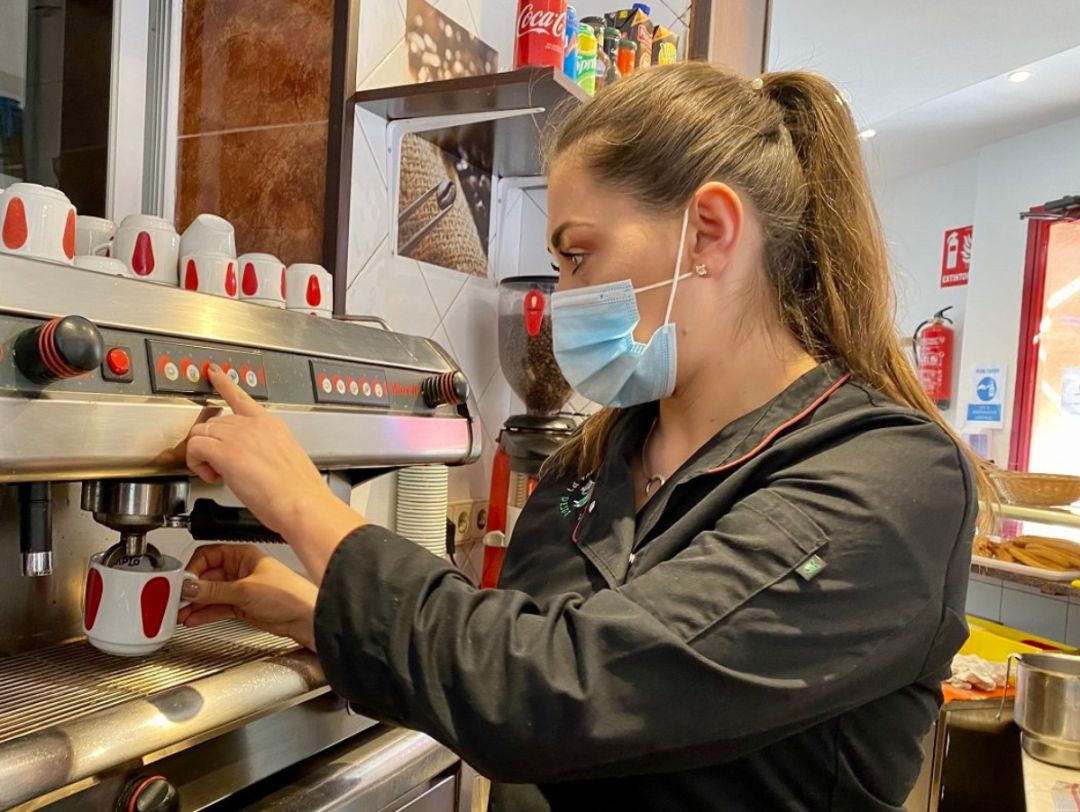 Una mujer sirve un café en un bar. Una mujer sirve un café en un bar.
