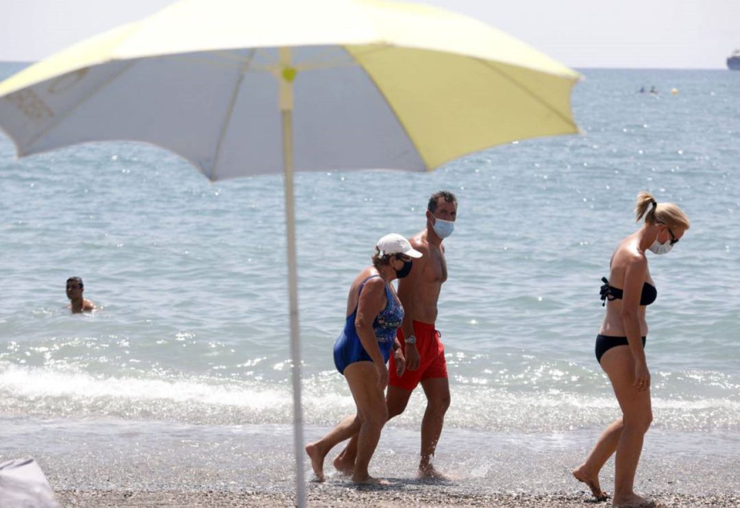 Archivo - Bañistas con mascarilla pasean por la orilla de una playa Archivo - Bañistas con mascarilla pasean por la orilla de una playa