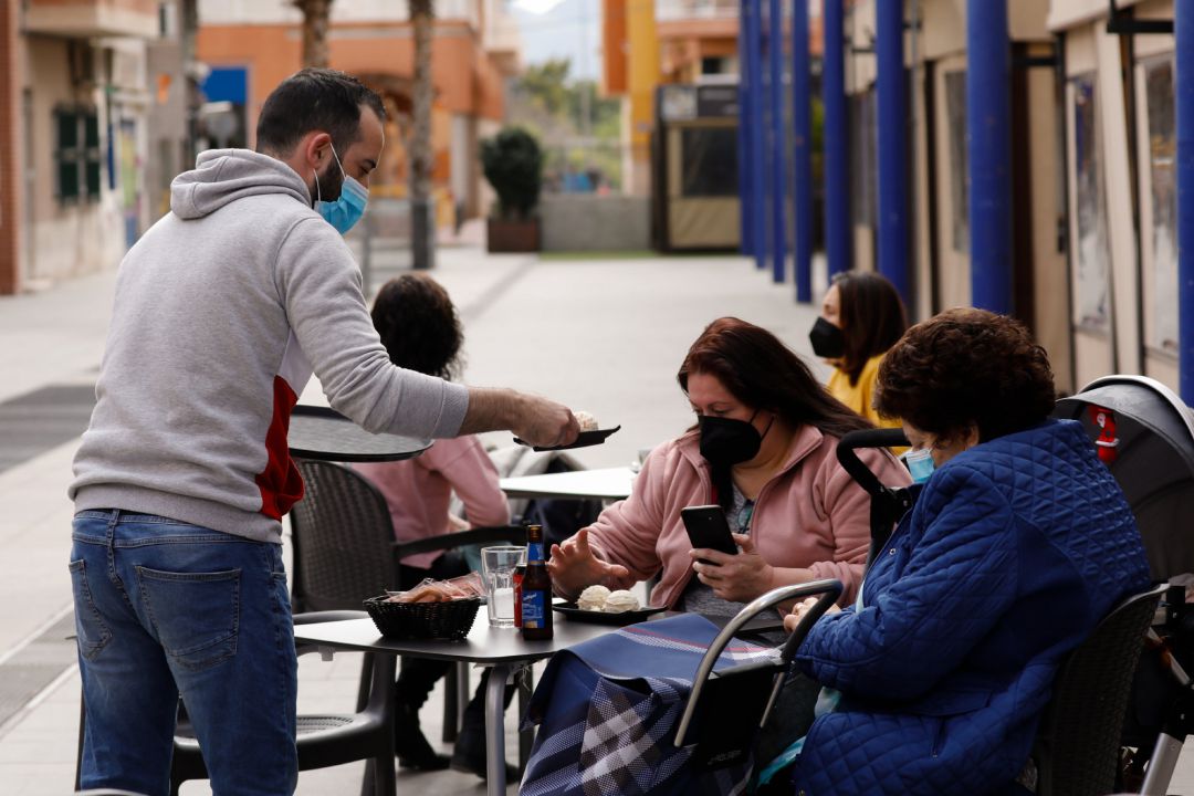 Un camarero atiende a dos clientas en la terraza de un bar. Un camarero atiende a dos clientas en la terraza de un bar.