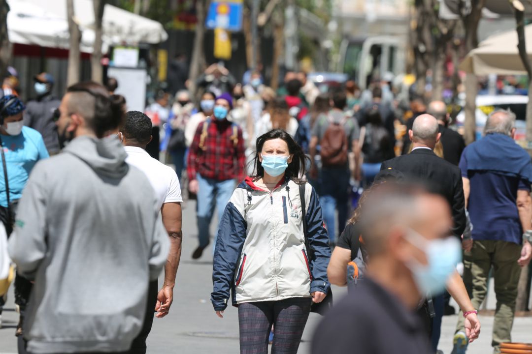 Varias personas caminan por el centro de una ciudad llevando mascarilla Varias personas caminan por el centro de una ciudad llevando mascarilla