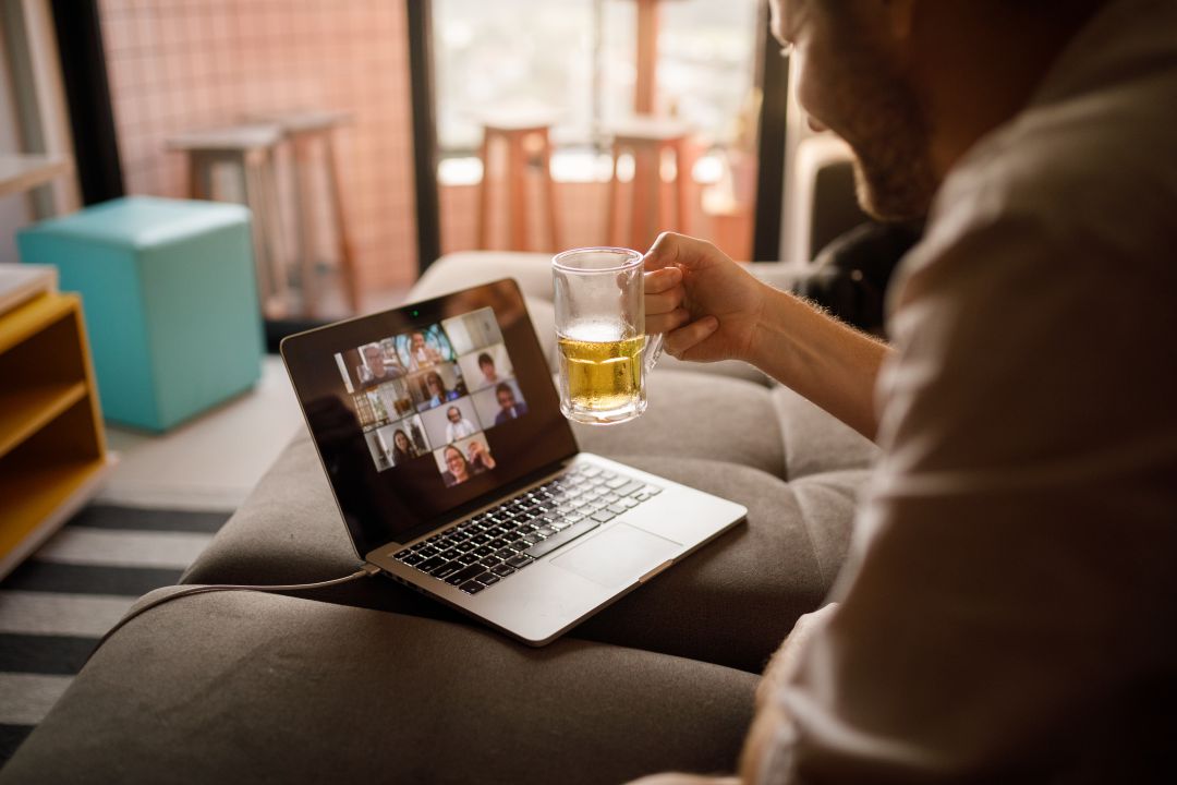 Una persona disfrutando de una cerveza durante una charla on line Una persona disfrutando de una cerveza durante una charla on line