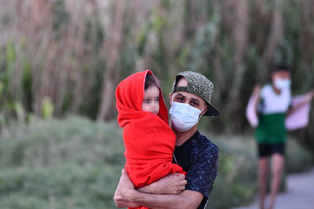 Un hombre migrante coge en brazos a una niña en la playa del Tarajal, a 17 de mayo de 2021, en Ceuta, (España). Un hombre migrante coge en brazos a una niña en la playa del Tarajal, a 17 de mayo de 2021, en Ceuta, (España).