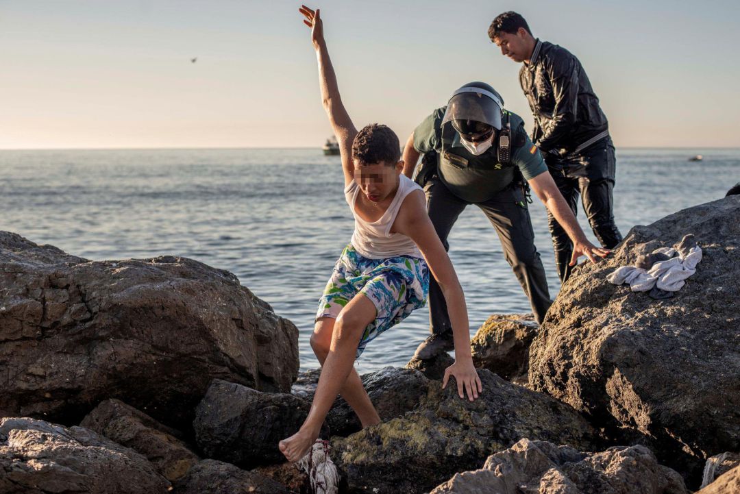 Un menor inmigrante es acompañado por un guardia civil a su llegada este miércoles a nado a la playa ceutí de El Tarajal. Un menor inmigrante es acompañado por un guardia civil a su llegada este miércoles a nado a la playa ceutí de El Tarajal.