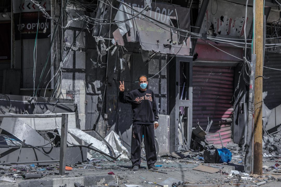Un hombre palestino hace la señal de la victoria junto a un edificio en ruinas bombardeado por Israel, el pasado martes. Un hombre palestino hace la señal de la victoria junto a un edificio en ruinas bombardeado por Israel, el pasado martes.