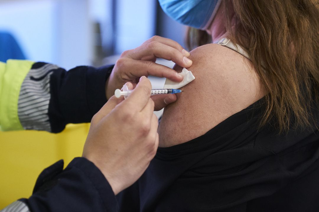 Un sanitario vacunando a una mujer Un sanitario vacunando a una mujer