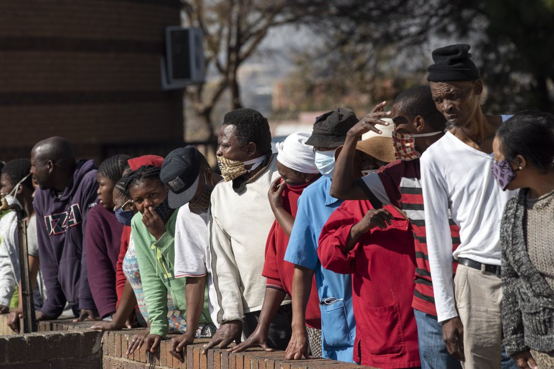 Gente con mascarilla en una cola para el reparto de comida en Johannesburgo, Sudáfrica. Gente con mascarilla en una cola para el reparto de comida en Johannesburgo, Sudáfrica.