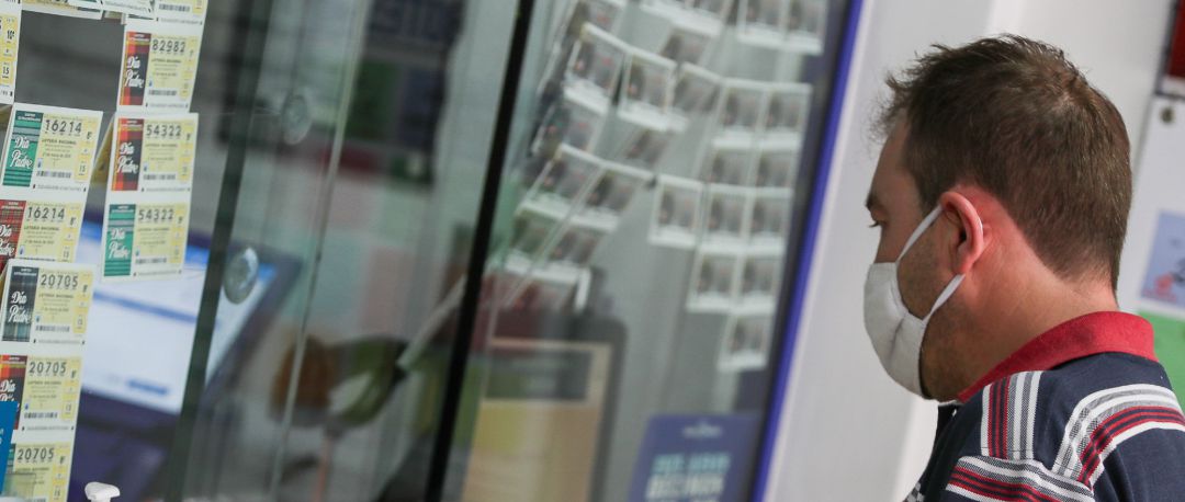 Un hombre compra lotería en una administración Un hombre compra lotería en una administración