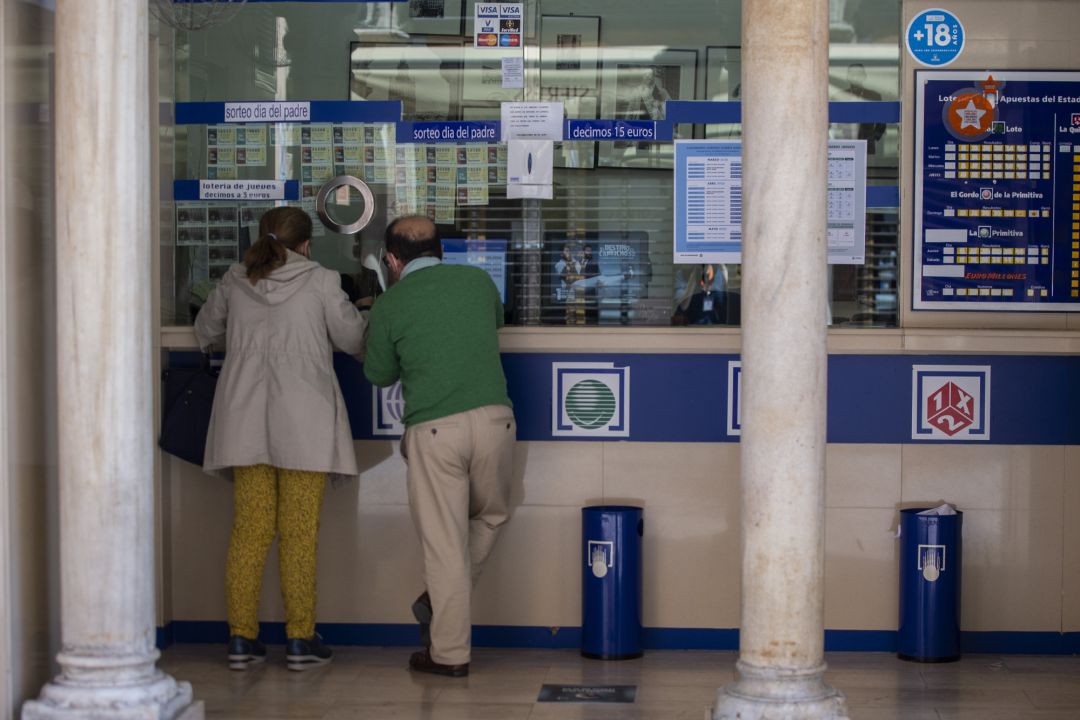 Dos personas compran lotería en una Administración. Dos personas compran lotería en una Administración.