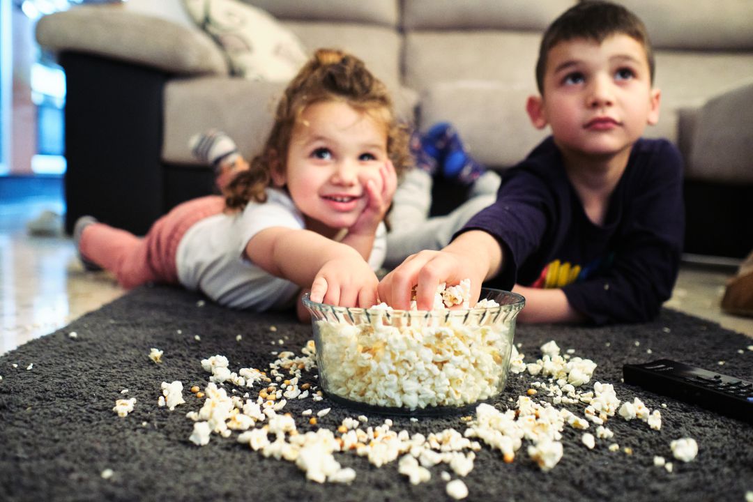 Niños viendo la tele mientras comen palomitas. Niños viendo la tele mientras comen palomitas.