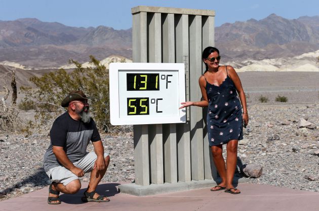 Una pareja de turistas posa frente al termómetro que marca 55 grados. Una pareja de turistas posa frente al termómetro que marca 55 grados.