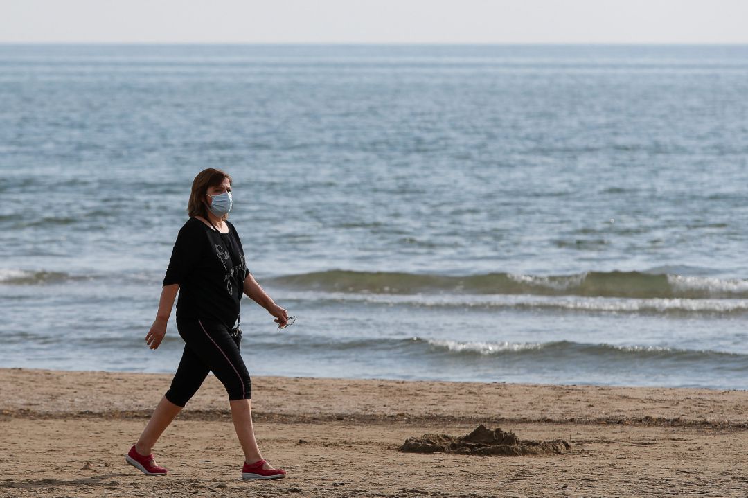 Archivo - Una mujer con mascarilla pasea por la playa de la Malvarrosa Archivo - Una mujer con mascarilla pasea por la playa de la Malvarrosa