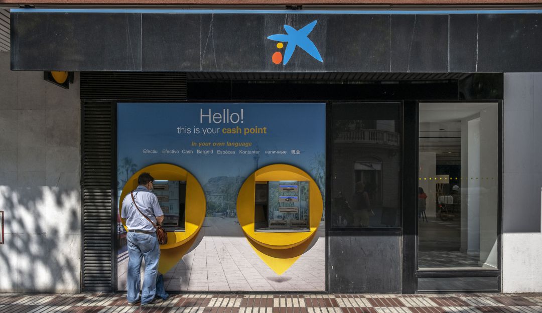 Una persona sacando dinero de un cajero. Una persona sacando dinero de un cajero.