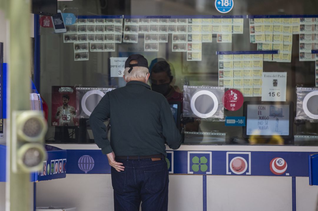 Una persona compra lotería en una administración Una persona compra lotería en una administración