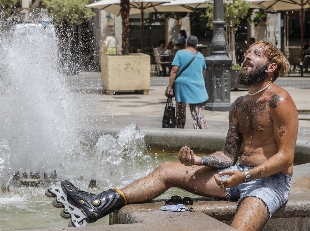 Un hombre se refresca en una fuente. Un hombre se refresca en una fuente.
